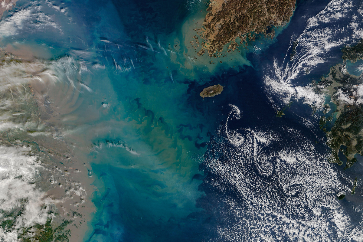 Jeju Adası'nın doğusunda spiral bulut sokakları ve batıda kahverengi tortu bulutu; NASA Terra MODIS görüntüsü