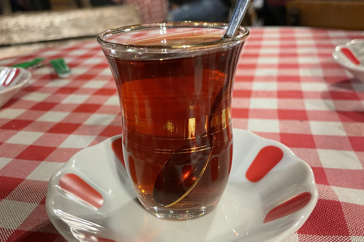 Kırmızı beyaz kareli örtü üzerinde ince belli bardakta demli çay
