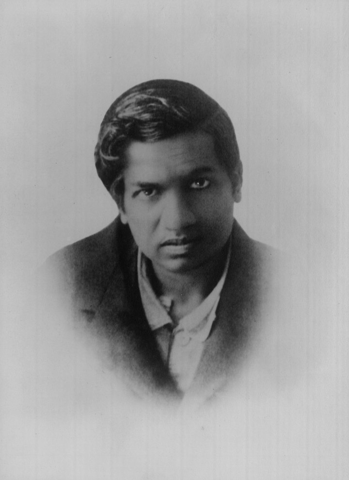 Srinivasa Ramanujan'ın siyah ceketli, açık yakalı gömlekli siyah beyaz vesikalık fotoğrafı