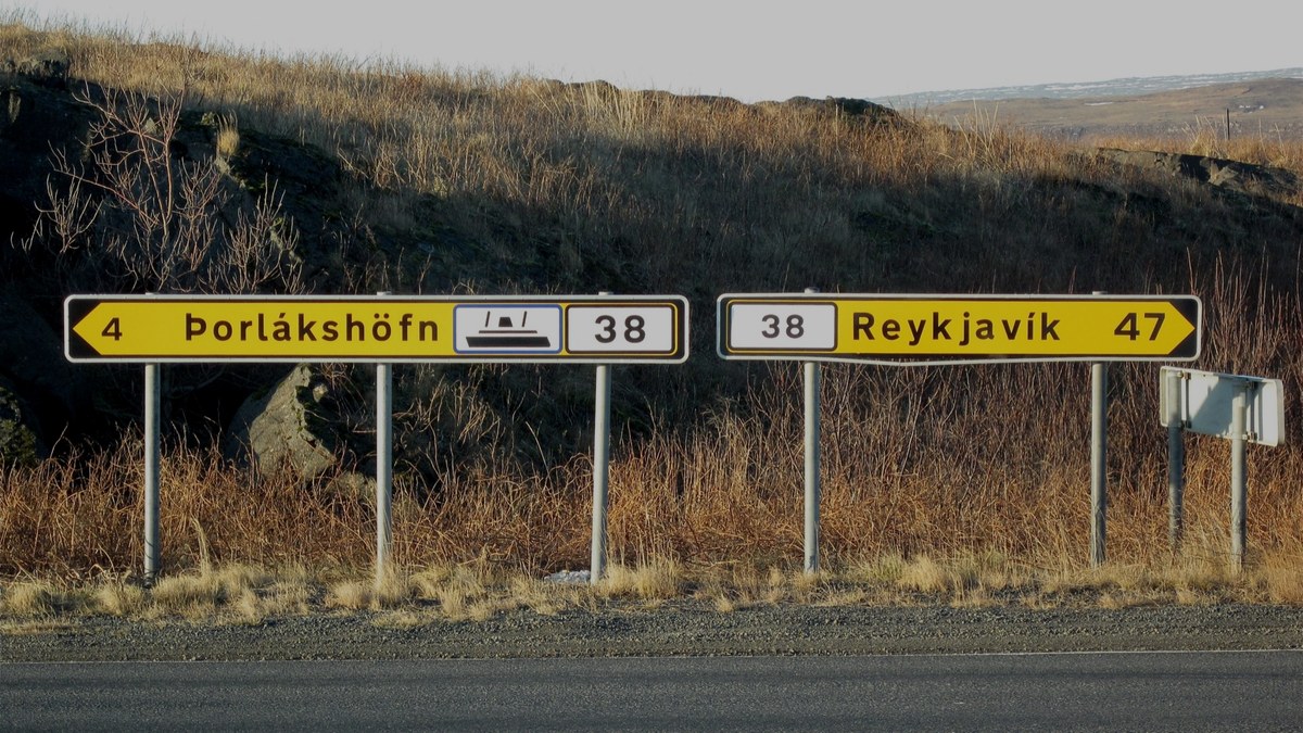 İzlanda'da iki yönlü yol levhası; sağa doğru asfalt yol, sola çakıllı bir yan yol