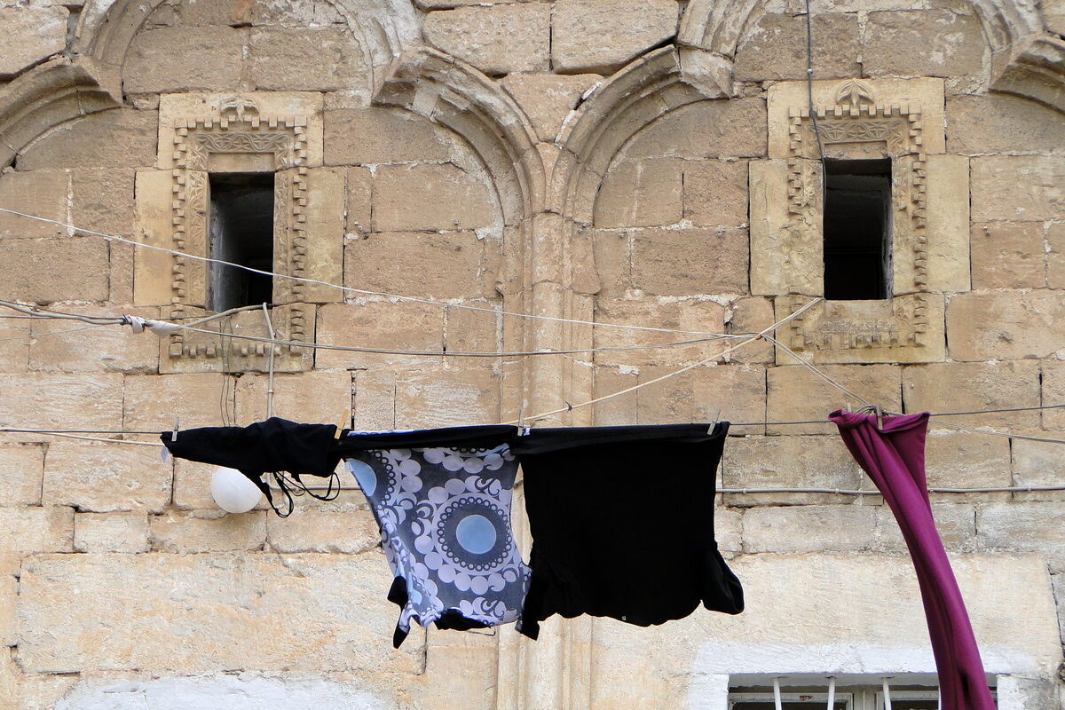 Mardin'de taş bir binanın önünde ipe asılmış koyu renkli çamaşırlar