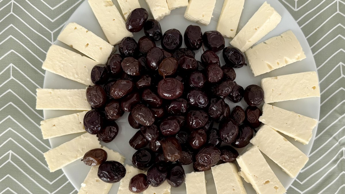 Tabakta beyaz peynir dilimleri ve yeşil zeytin
