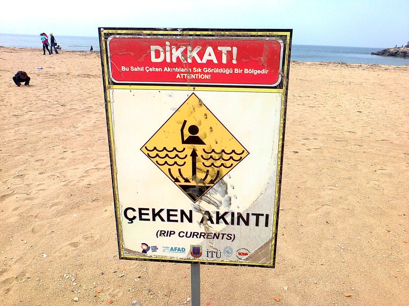 Ağva plajında kuma dikilmiş Dikkat Çeken Akıntı uyarı levhası