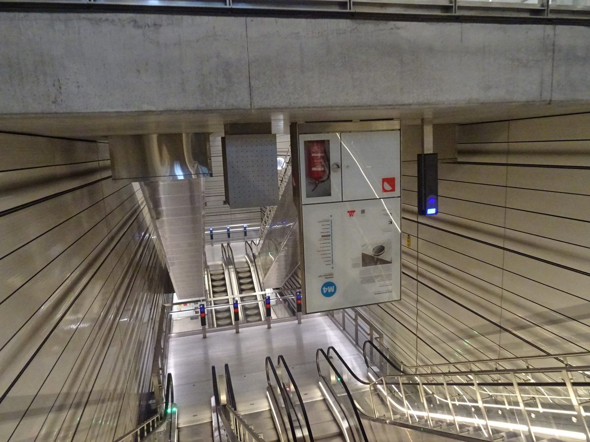 Havneholmen istasyonunda yürüyen merdivenlerin üstündeki tavana baş aşağı monte edilmiş metro bilgi panosu ve kart okuyucu, aşağıda merdivenler