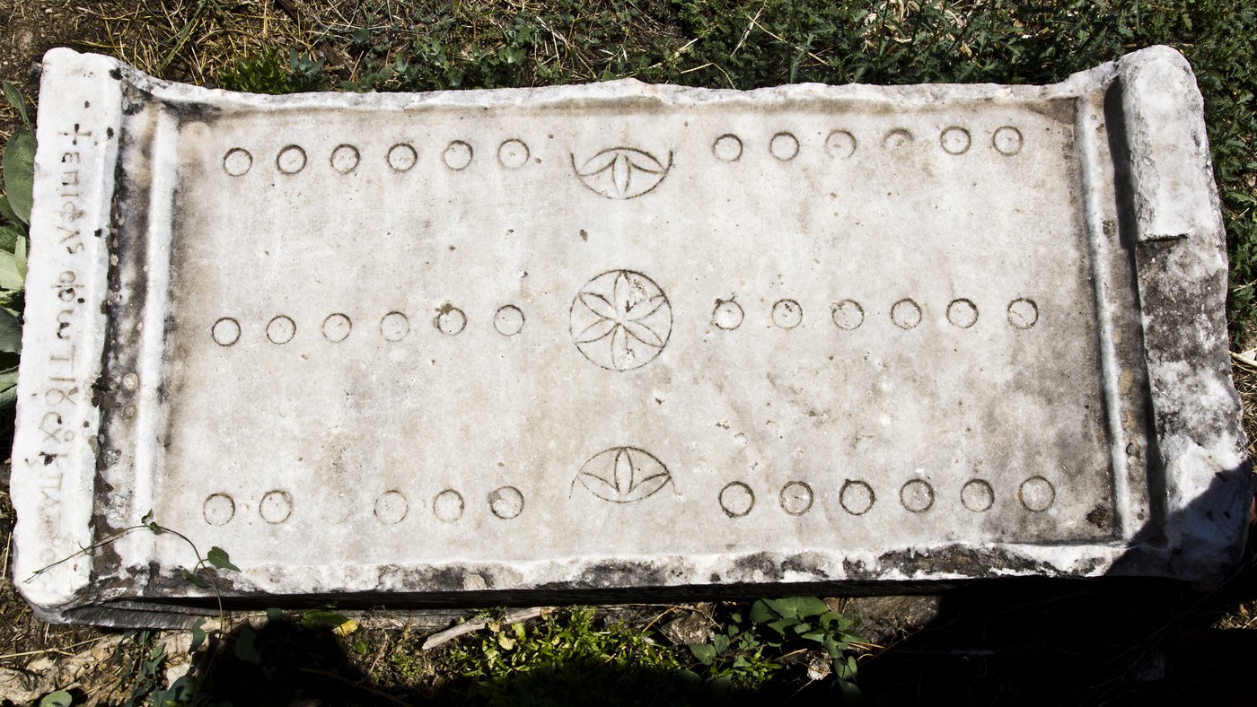 Afrodisias'ta mermere oyulmuş, üç sıra yuvarlak işaret ve ortada rozet motifleri olan Roma oyun tahtası