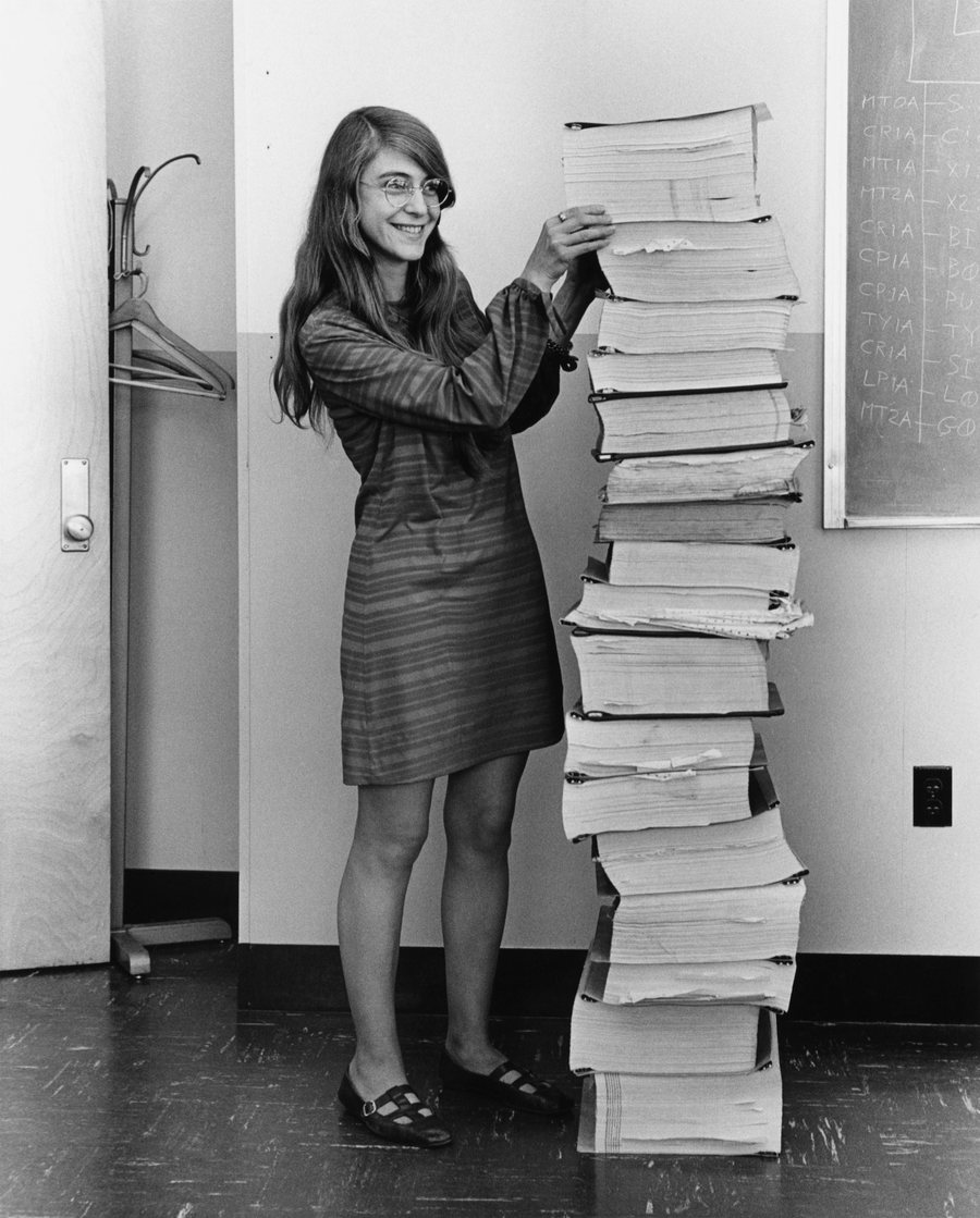 Margaret Hamilton 1969'da MIT'de, kendi boyuna ulaşan üst üste yığılmış uçuş yazılımı çıktılarının yanında gülümserken