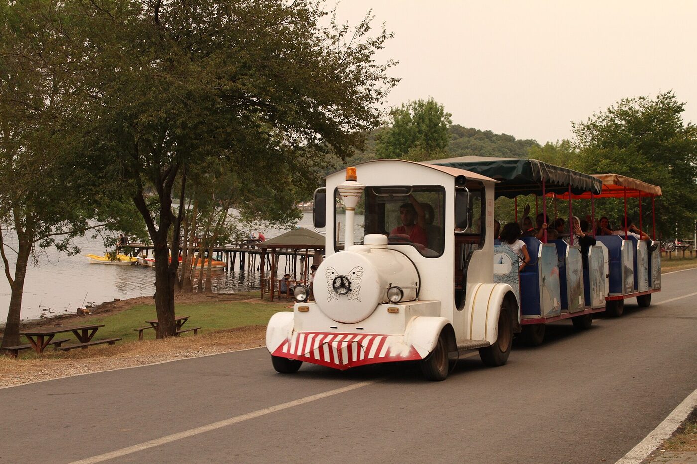 Park içindeki asfalt yolda ziyaretçi taşıyan küçük tur treni
