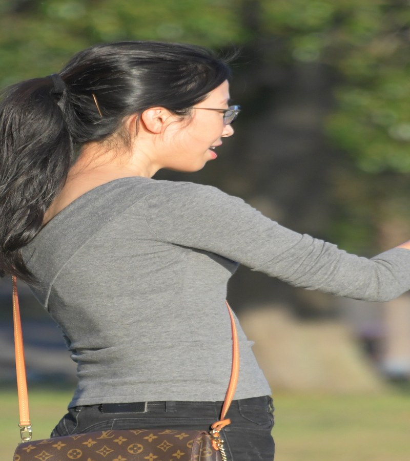 Sidney Centennial Park'ta cep telefonuna bakan bir kız çocuğu