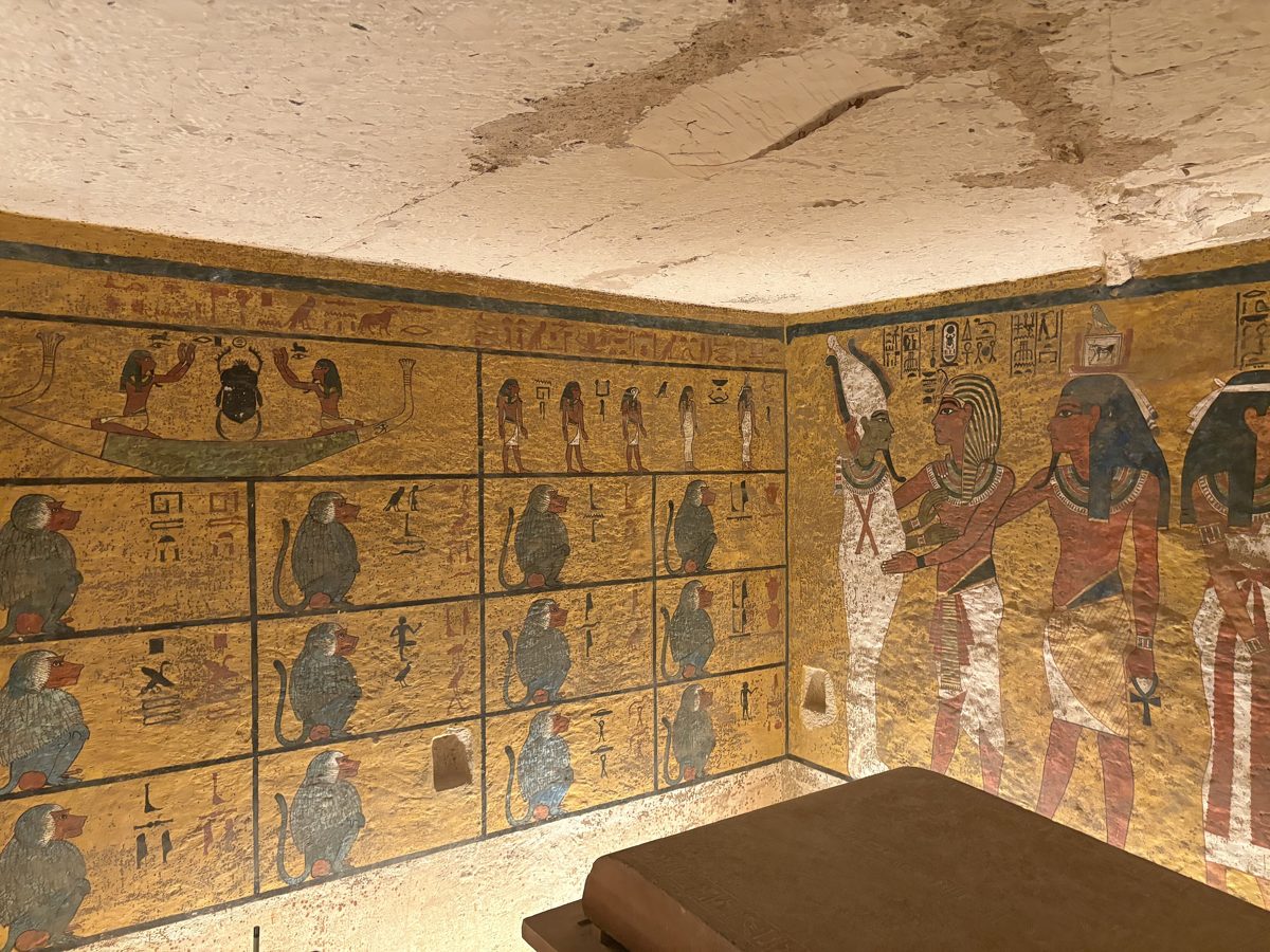 Gömü odasının köşesi: solda ızgara biçiminde bölmelere yerleştirilmiş on iki babun resmi, sağda Osiris'in Tutankamon'u kucakladığı sahne, altta lahdin kenarı