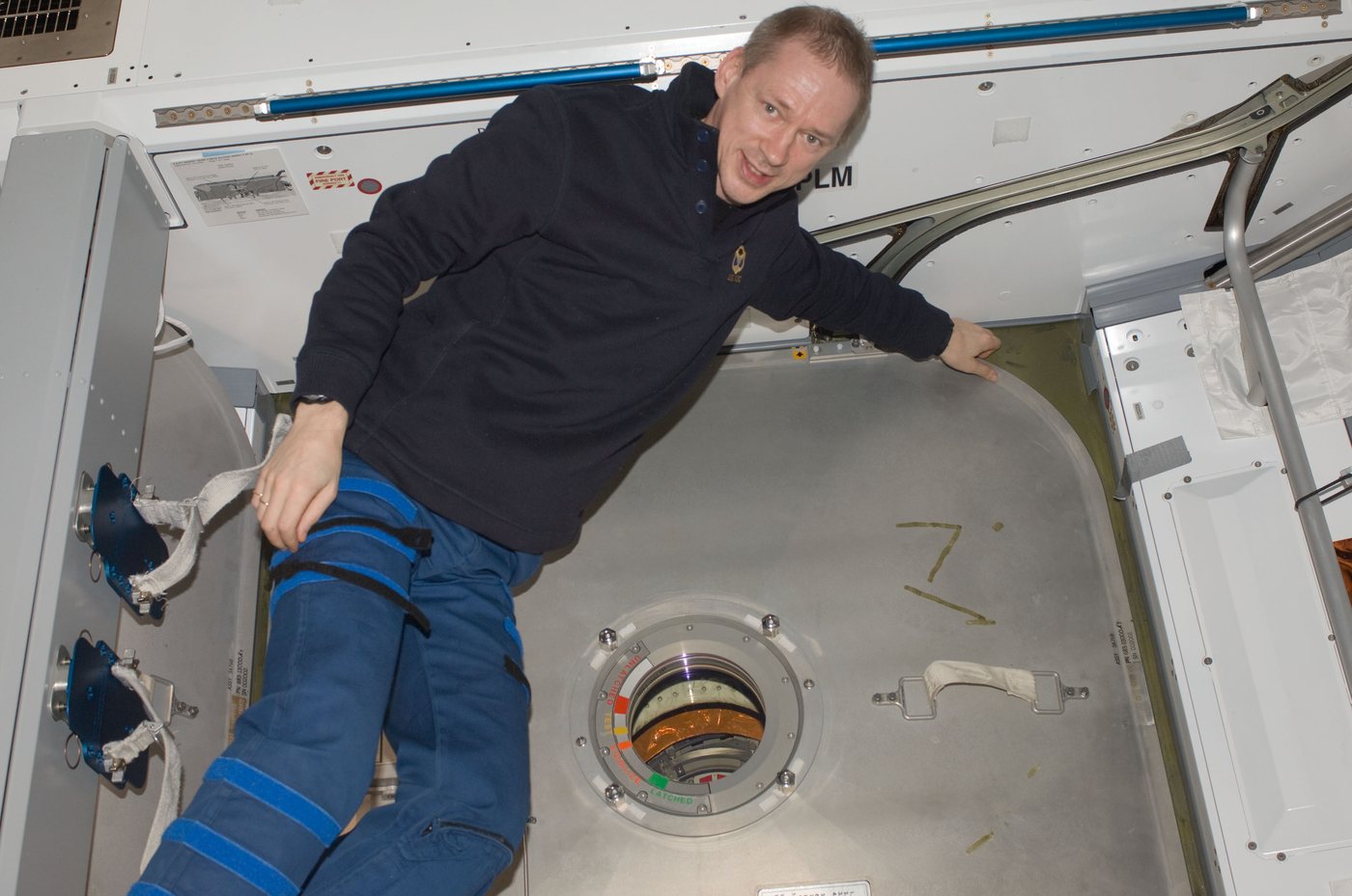 ESA astronotu Frank De Winne, Uluslararası Uzay İstasyonu'nun Harmony modülündeki köşeleri yuvarlatılmış büyük kare yanaştırma kapağının önünde süzülüyor