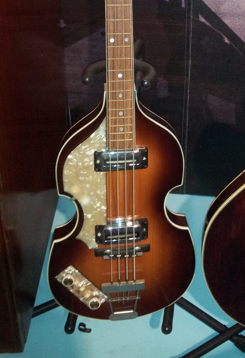 Vitrinde duran, sedef koruyuculu, kahverengiden sarıya açılan keman gövdeli solak bir Höfner bas gitar